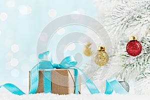 Christmas gift or present box and fir tree with balls decorations against turquoise bokeh background. Holiday greeting card.