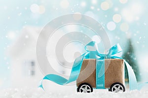 Christmas gift or present box on wheels against turquoise bokeh background. Holiday greeting card.