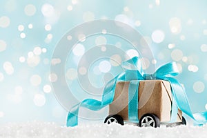 Christmas gift or present box on wheels against turquoise bokeh background. Holiday greeting card.