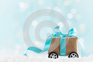 Christmas gift or present box on wheels against turquoise bokeh background. Holiday greeting card.