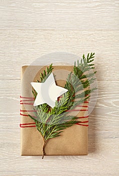 Christmas gift present with recycled wrapping paper and natural decorations on rustic wood background