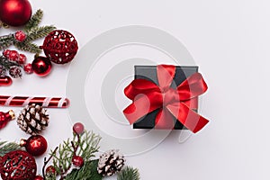 Christmas gift with a red bow on a white background with fir branches and decorations on a white background. View from