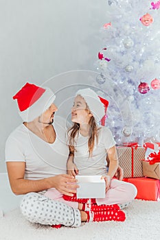 Christmas gift surprise - A little girl opens a Christmas present in amazement. The father gives his daughter a gift on