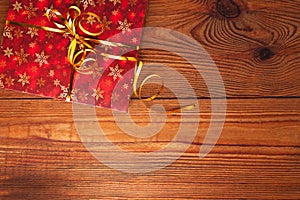 Christmas gift, trendy red present box wrapped with golden ribbon decoration on rustic wooden background. Flatlay style