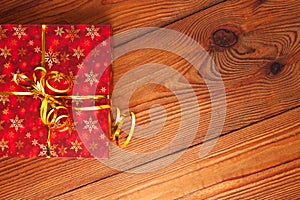 Christmas gift, trendy red present box wrapped with golden ribbon decoration on rustic wooden background. Flatlay style