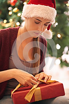 Christmas, gift and woman on floor in living room on xmas eve, content and calm while wrapping ribbon. Festive, holiday