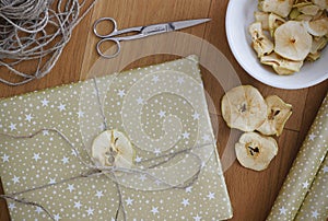 Christmas gift wrapped in golden wrapping paper, decorated with dried apple