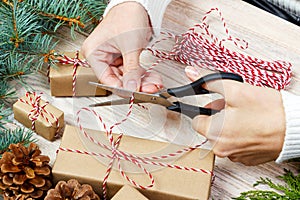 Christmas gift wrapping background. Female hands packaging christmas present with red ribbon, top view. Winter holidays