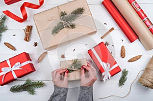 Christmas gift wrapping background. Female hands packaging christmas present wrapped in kraft paper, top view.