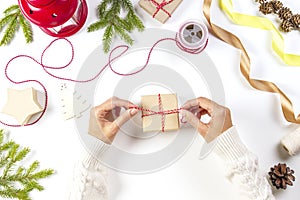 Christmas gift wrapping. Woman`s hands packing Christmas presents on white table