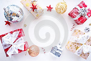 Christmas gifts, Christmas balls, red stars, bows and a disco ball on a white table.