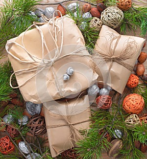 Christmas gifts in craft paper package tied a rope on wooden background in a frame christmas tree branches decorations.