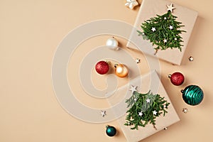 Christmas gifts decorated fir branches with colorful xmas balls ornaments on beige background