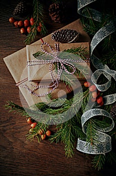 Christmas gifts, fir twigs and rose hips on old wooden table