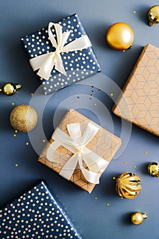 Christmas gifts and gold baubles on dark blue background. Elegant Christmas flat lay composition. Happy New Year and Merry