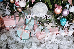 Christmas gifts packed with pink,tiffany paper and tapes under decorated tree.