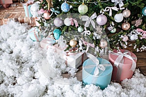 Christmas gifts packed with pink,tiffany paper and tapes under decorated tree.