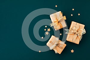 Christmas gifts or presents with golden bow ribbon and star confetti on green background top view. Flat lay