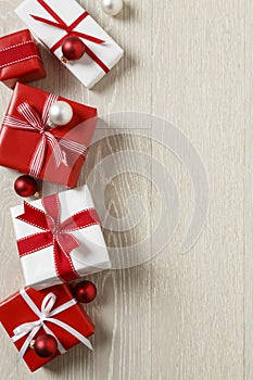 Christmas gifts presents on rustic wood background. Simple, red and white gift boxes festive holiday border.