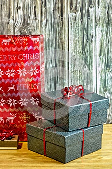 Christmas gifts with red ribbon on table and wood background