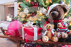 Christmas gifts and teddy bears under decorated Christmas tree.