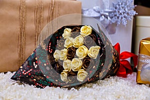 Christmas gifts under the Christmas tree red and wooden toys brick wall, in foreground bouquet of chocolate flowers