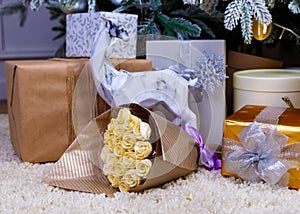 Christmas gifts under the Christmas tree red and wooden toys brick wall, in foreground bouquet of chocolate flowers