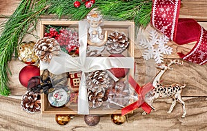 Christmas gifts in a wooden box on a wooden background. Christmas tree branches, decorations, cones, angel and gifts