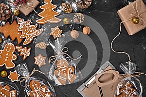 A Christmas gingerbread cookie in the shape of a Christmas tree in a cellophane packing on the background of a dark