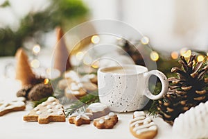 Christmas gingerbread cookies, coffee, pine cones  and warm lights on white wooden table