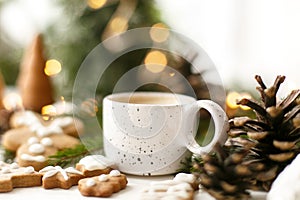 Christmas gingerbread cookies, coffee, pine cones  and warm lights on white wooden table