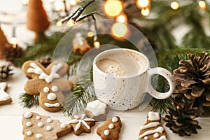 Christmas gingerbread cookies, coffee, pine cones  and warm lights on white wooden table