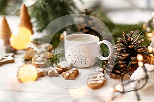 Christmas gingerbread cookies, coffee, pine cones  and warm lights on white wooden table