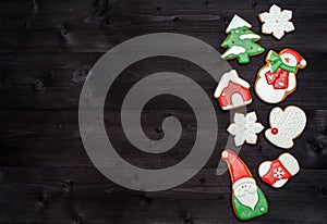 Christmas gingerbread cookies on dark wood background, copy space. Top view, flat lay. Santa, snowflake, mitten, house, stocking.