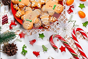 Christmas gingerbread cookies homemade on red plate with branches of Christmas tree and decor on home New Year table. Merry Chris