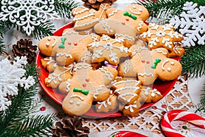 Christmas gingerbread cookies homemade on red plate with branches of Christmas tree and decor on home New Year table. Merry Christ