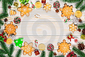 Christmas gingerbread cookies homemade on wooden table with candies, Christmas tree branches and New Year decorations.