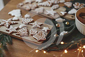 Christmas gingerbread cookies with icing on festive rustic table with decorations and golden lights. Merry Christmas! Delicious