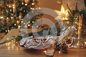Christmas gingerbread cookies with icing in plate on festive rustic table with decorations against golden illumination. Merry