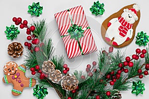 Christmas gingerbread cookies and New Year decorations on white background. Greeting card with a gift, fir branches, pine cones