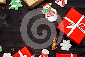 Christmas gingerbread cookies, red gift boxes, cinnamon, anise stars on dark wooden background, copy space.