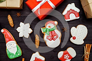 Christmas gingerbread cookies, red gift boxes, cinnamon ans anise stars on dark wooden background, copy space.