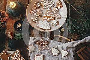 Christmas gingerbread cookies on rustic table with napkin, candle, decorations, spices. Flat lay. Atmospheric moody image. Making