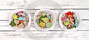 Christmas gingerbread cookies on three plates by wooden table