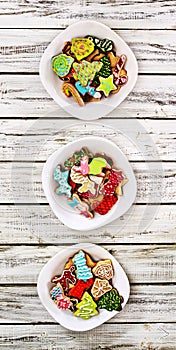 Christmas gingerbread cookies on three plates by wooden table