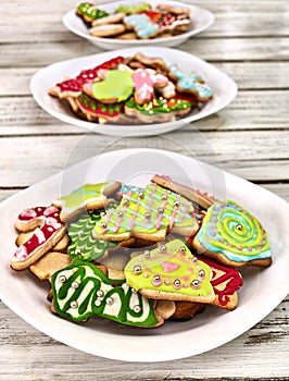 Christmas gingerbread cookies on three plates by wooden table