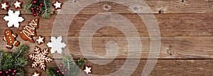 Christmas gingerbread cookies and tree branches, above view corner border banner on a wood background