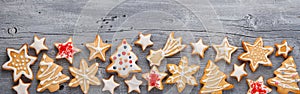 Christmas gingerbread cookies in white icing glaze in form of fir tree, stars and snowflakes on rustic wooden background, wide