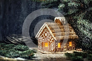 Christmas Gingerbread House with Window Lights in Winter Snowy Forest Night. Creative Food Decoration Design for Xmas Holiday