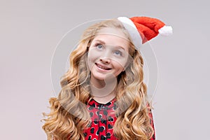 Christmas girl. Beautiful teen model in santa hat isolated on background